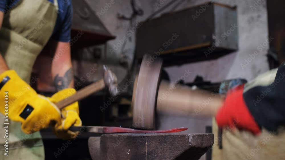 Private forge. A blacksmith and his assistant forge metal products on an anvil in a private forge. Private forge. A blacksmith and his assistant forge metal products on an anvil in a private forge.