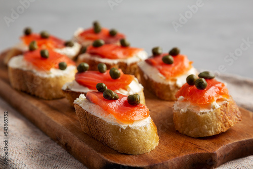 Homemade Lox And Cream Cheese Crostini on a wooden board, side view. Close-up.