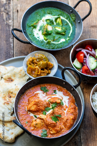 Butter chicken, saag paneer, toamto salad and naan bread photo
