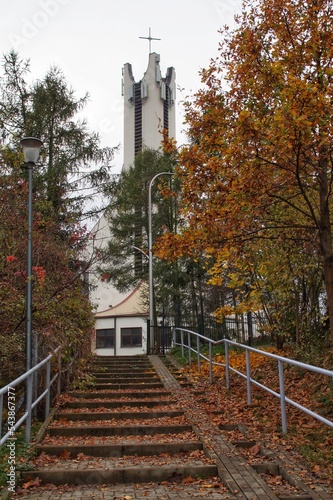 Autumn trees and stairs covered with leaves against the background of the tower of the church of St. Józef in Plock