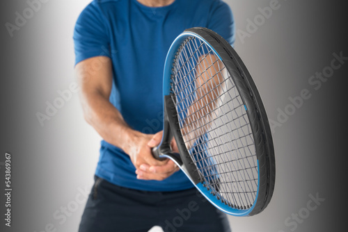 A male tennis player holding a tennis racket with a determined expression and eyes on a white background. © Naypong Studio