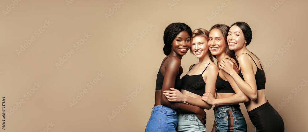 Multi Ethnic Group of Womans with diffrent types of skin standing together and looking on camera. Diverse ethnicity women - Caucasian, African and Asian against beige background - obrazy, fototapety, plakaty 