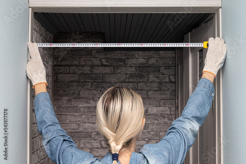 Woman measuring a doorway with a tape measure. woman using a tape measure (Corrected).