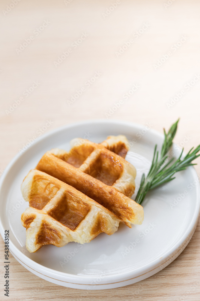 Trendy delicious croffle on white plate on wood background. Copy space. Trendy delicious croffle on white plate on wood background. Copy space.