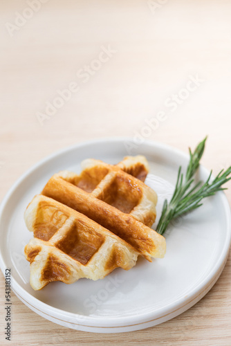 Trendy delicious croffle on white plate on wood background. Copy space.