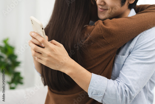 Cheating on girlfriends concept, unfaithful Asian man looking at mobile phone text during embracing with his lover