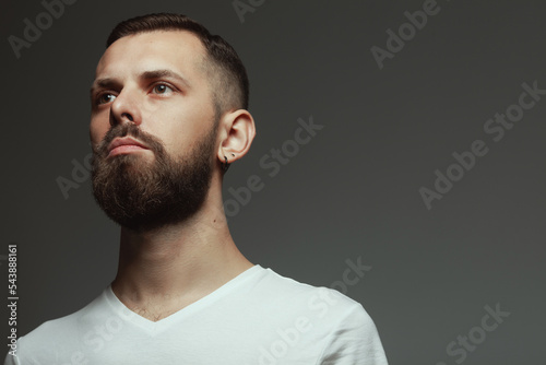 Male beauty concept. Portrait of proud charismatic active 30-year-old man posing over dark gray background. Perfect haircut. Hipster style. Close up. Copy-space. Studio shot