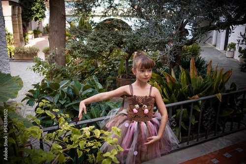 Niña pequeña posando bailar ballet con tutú rosa y marrón frente a un jardín precioso en un entorno románico photo