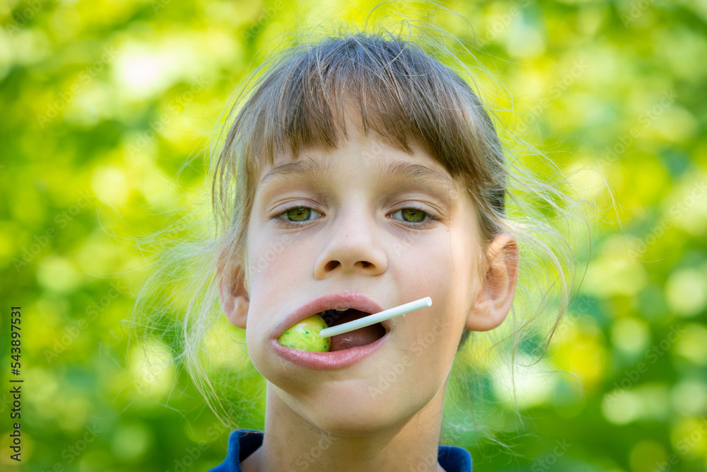 The girl has a big round lollipop in her mouth, close-up portrait The girl has a big round lollipop in her mouth, close-up portrait