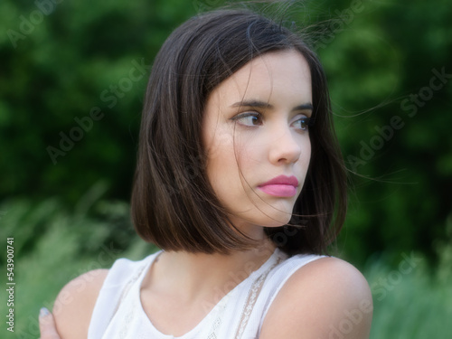 Young woman in white dress standing in the nature on a beautiful summer day