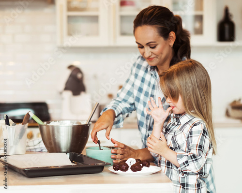 Mom with her 4 years old daughter are cooking in the kitchen to Mothers day, Family creativity, joint activities with children.