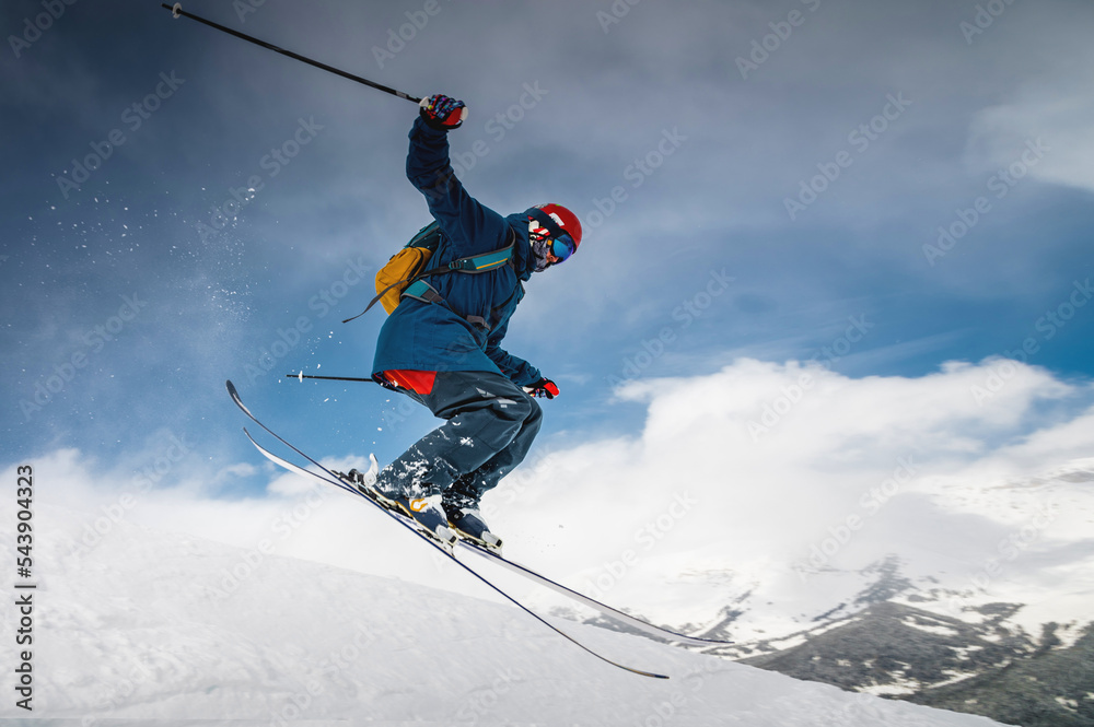 male skier jumping from mountain creating snow plume, winter extreme sport, downhill skiing
