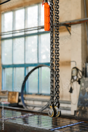 Industrial crane equipment. Metal hooks on chains and control panel.