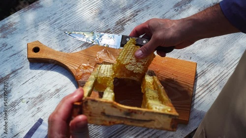 Natural dessert. A man cuts honeycombs on the sun on the table. Healthy food concept. eco natural food. Bee Honey. High quality 4k footage