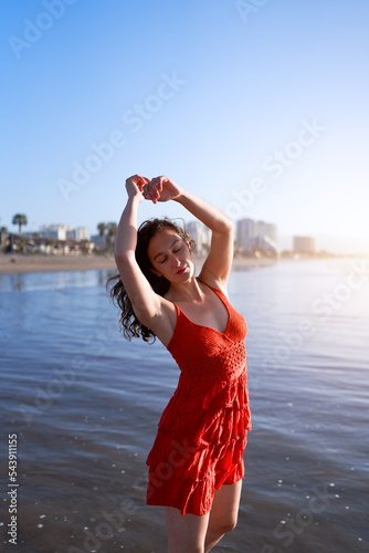 young latin woman with her arms above her head in the sea enjoying the sun and the breeze photo
