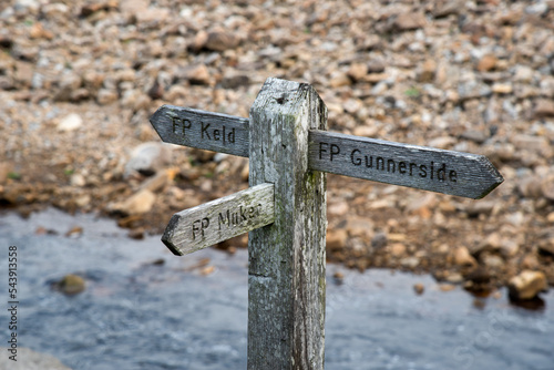 Wooden sign showing the direction to Kled, Muker and Gunnerside at the river swale in the Swaledale in Yorkshire, UK. photo