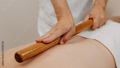 Man's back during traditional thai massage with stick. Oriental alternative medicine with wooden tools. Body care and SPA in Thailand resort
