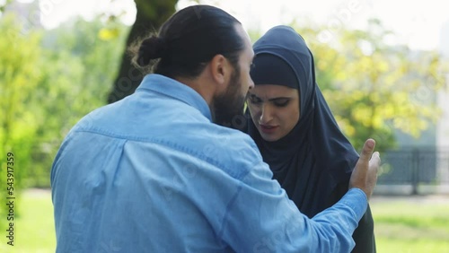 Aggressive Arab husband yelling threatening scared wife outdoors, family abuse
