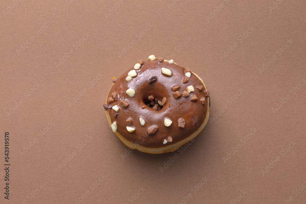 Ciambella con glassa al cioccolato e scaglie di cioccolato su superficie marrone Ciambella con glassa al cioccolato e scaglie di cioccolato su superficie marrone