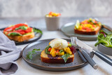 Assorted of open brioche sandwich with salmon, avocado, poached egg and mango salsa served with arugula and salad leaves. Healthy breakfast concept.