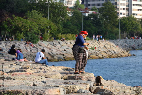 selective focus: middle aged woman selling red roses to couples on the beach of kadikoy fashion photo