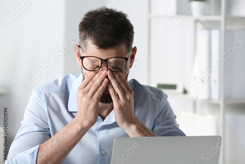 Fotografija Man suffering from eyestrain at workplace in office