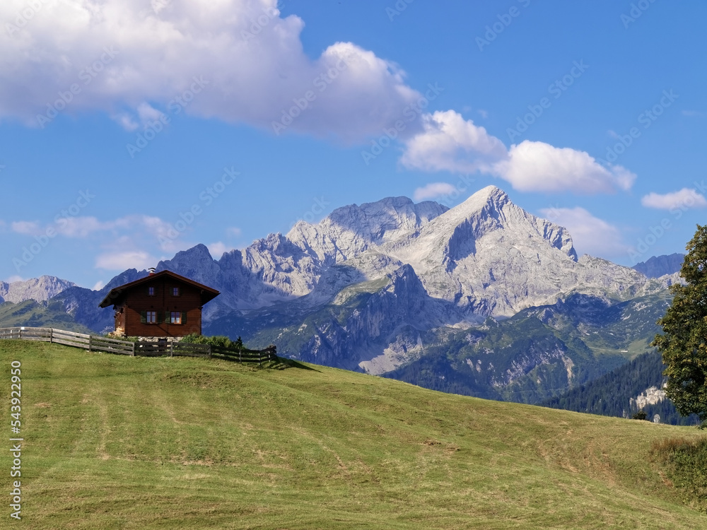In the foreground a mountain meadow with a mountain hut, in the background the Wetterstein Mountains