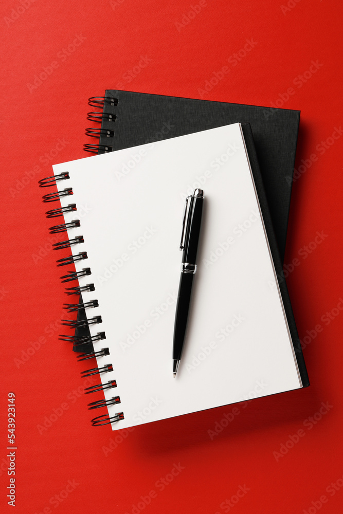 Notebooks and pen on red background, top view Notebooks and pen on red background, top view