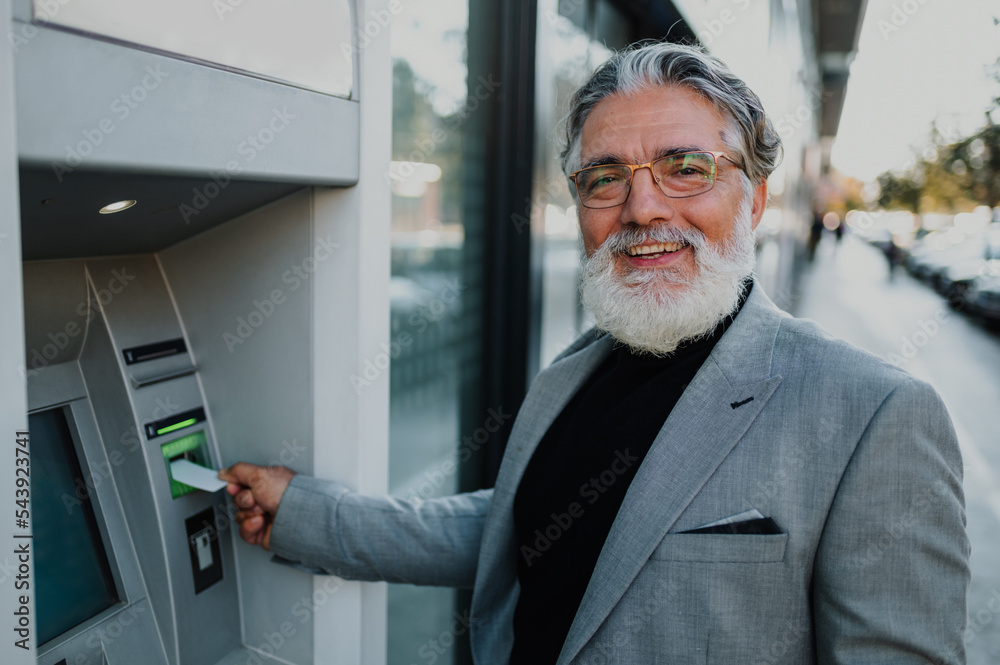 Senior business man using atm machine and credit or debit card Senior business man using atm machine and credit or debit card
