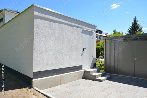 Rückseite einer modernen Beton-Garage mit Hintertür und benachbarte Gerätehütte auf dem Wohngrundstück