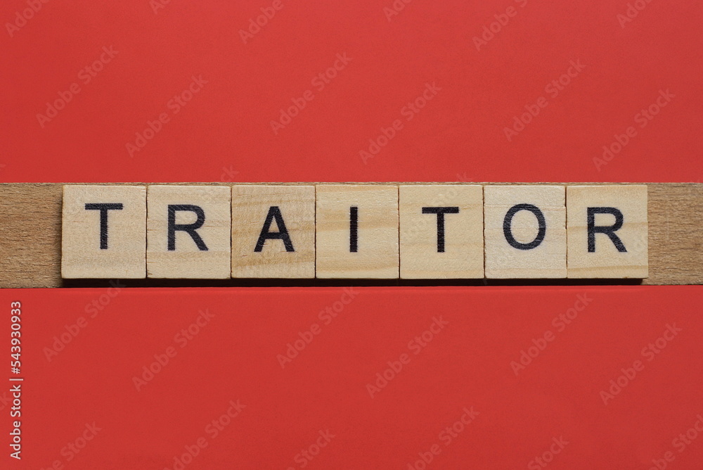 text the word traitor from gray wooden small letters with black font on an red table