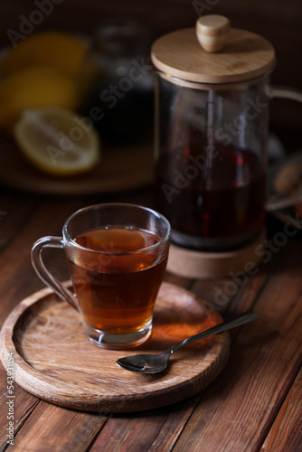 Glass cup with delicious tea on wooden table