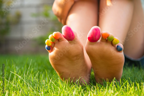 Teenage girl with painted toes sitting on green grass outdoors, closeup © New Africa