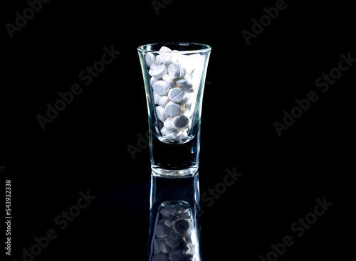 white orange pills in wineglass glass . in jar. in bucket Isolated on black set of capsule and pills inside closeup,