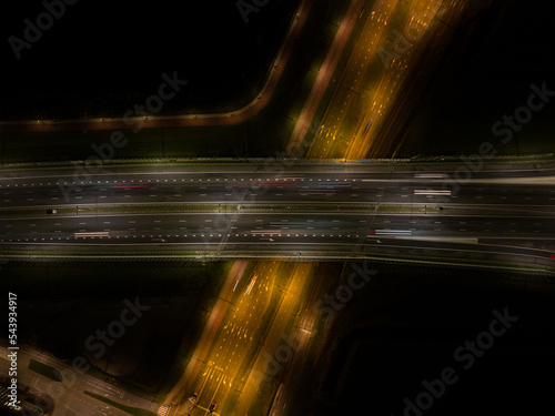 A10 Highway traffic at night. Motorway infrastructure in darkness light of dynamic moving traffic on the road at Amsterdam Ijburg in The Netherlands. Aerial drone night photography. Overhead overview.