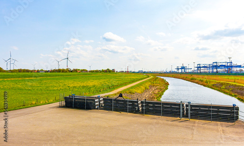 Industrial area cranes container dyke seascape panorama in Imsum Germany.