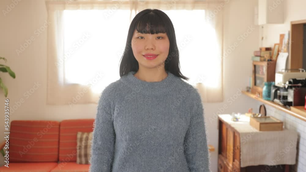 Young Asian woman smiles at her living room. Black long hair. Young Asian woman smiles at her living room. Black long hair.