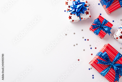 Forth of July celebration concept. Top view photo of present boxes with ribbon bows and star shaped confetti on isolated white background with blank space