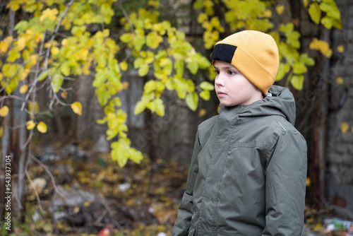 a boy in an orange hat looks forward in fright on a walk in autumn.