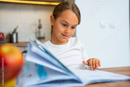 Close up of a little girl looking at her school book, she's looking for her homework assignment