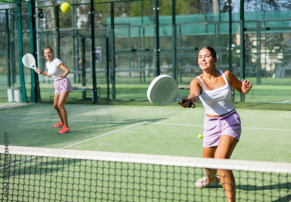 Active womans with enthusiasm playing padel on the tennis court