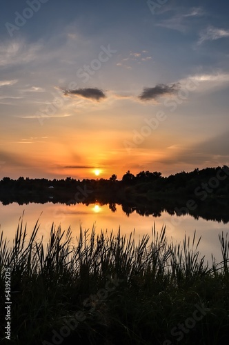 Wonderful, colorful summer landscape. Sunset in the beautiful sky over the lake. © shadowmoon30