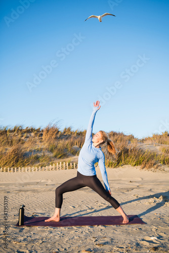 Young woman doing yoga at the beach during golden hour photo