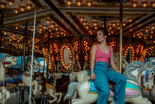 Teen girl sitting on carousel horse looking away