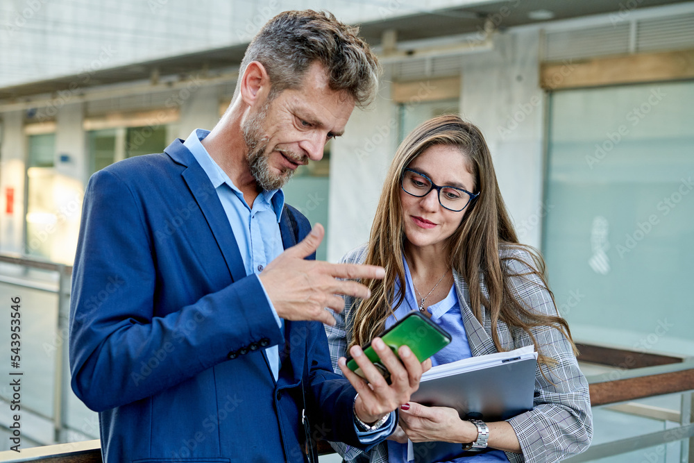 A business man and woman are discussing a presentation A business man and woman are discussing a presentation