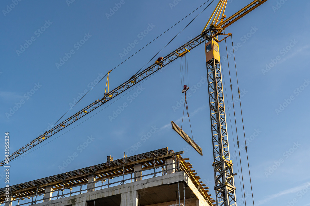 Construction site with cranes against blue sky. Industrial background. Modern skyscrapers. Unfinished construction Construction site with cranes against blue sky. Industrial background. Modern skyscrapers. Unfinished construction