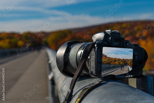 A camera on  Cantilever bridge in Walkway Over the Hudson State Historic Park with the Hudson river in the background in Autumn