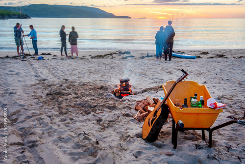 Young people gathered on Balnkeil Beach,to watch night time sunset,mid summer,northwest Scotland,UK. photo