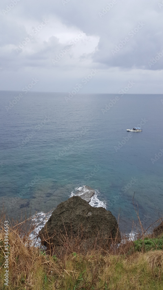 Okinawa, Japan. Small boat on the crystal clear sea. Horizontal sea and blue sky. Okinawa, Japan. Small boat on the crystal clear sea. Horizontal sea and blue sky.