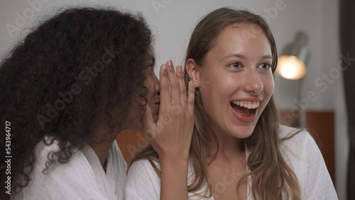 Two female friends having smile with good feeling on white bed